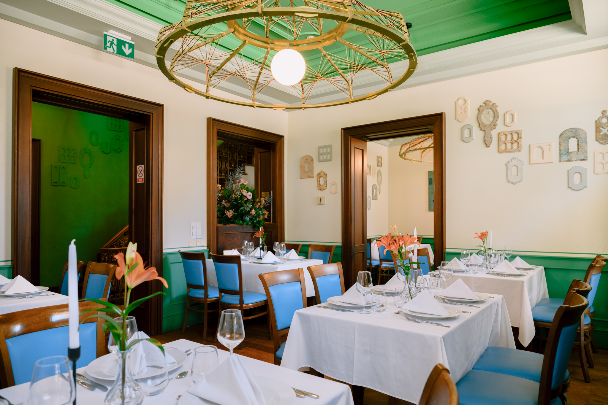 Idee - eveniment perfect Buongiorno 3 - Buongiorno Italian Elegant restaurant dining room with white tablecloths, blue chairs, green walls, and a large circular wicker chandelier.