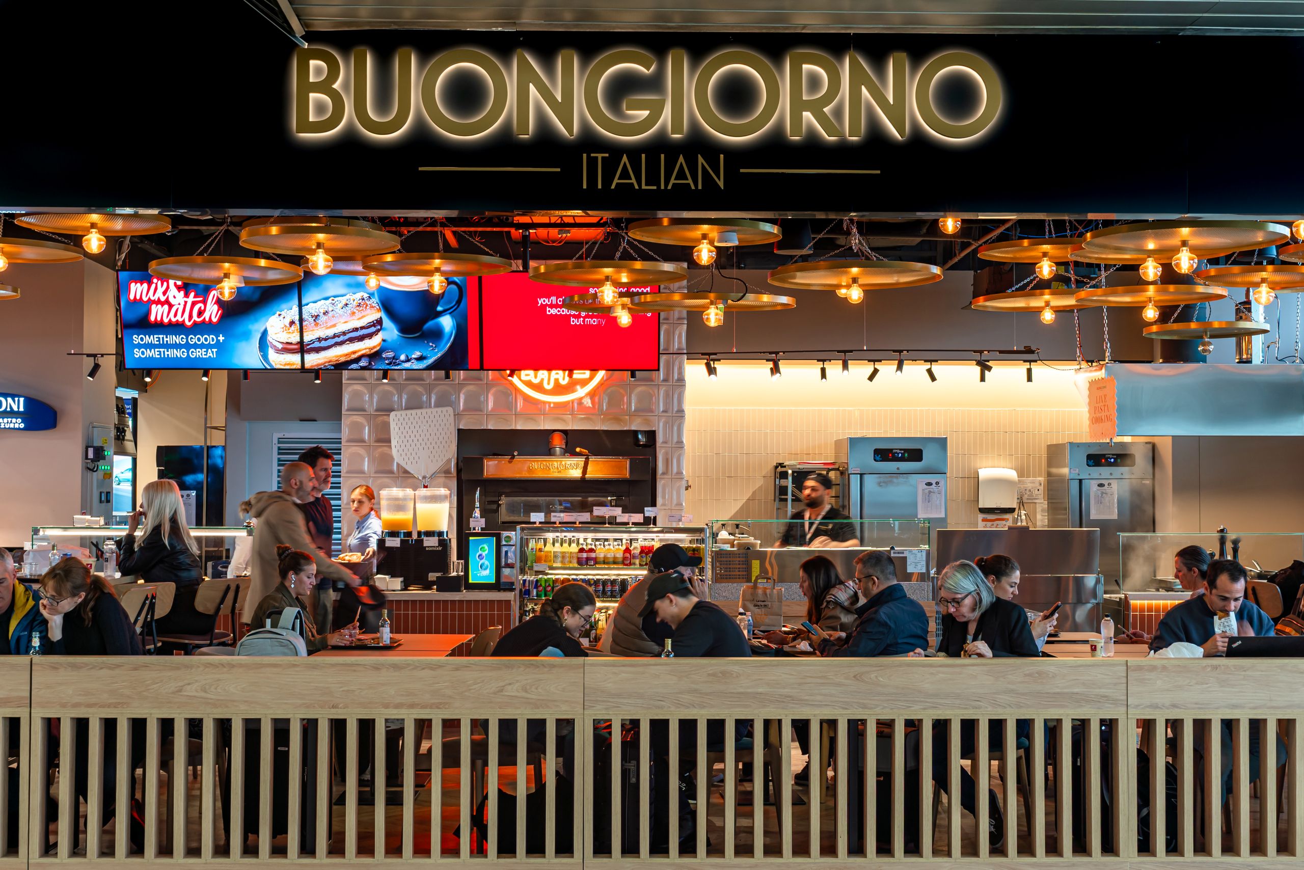 Bustling Italian cafe counter with warm hanging lights and customers seated at tables in the foreground